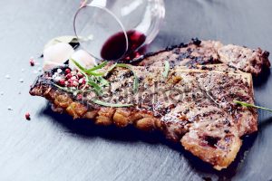 Steak with spices and glass of red wine on stone